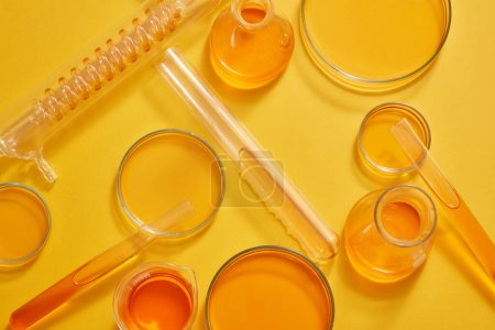 Foto de Artículos de vidrio de laboratorio llenos de soluciones naranjas decoradas con fondo naranja claro. Concepto pruebas de laboratorio e investigación natural extracto fabricación de cosméticos - Imagen libre de derechos