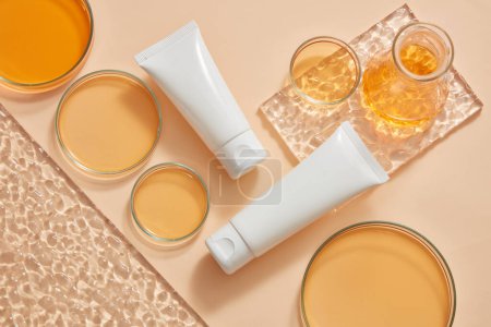 Glass petri dishes with many sizes and an erlenmeyer flask filled with orange fluid are arranged with unlabeled tubes. Skin care beauty product presentation mockup