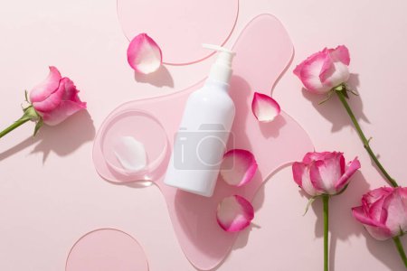 Pink acrylic sheet in geometric shape with pump bottle and a transparent podium with cream texture placed on. Natural beauty product concept of Rose (Rosa) extract