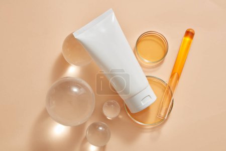 Foto de Una etiqueta vacía tubo blanco colocado en bolas de vidrio y placas de Petri, tubo de ensayo que contiene soluciones de color naranja. Producción de productos cosméticos de belleza en concepto de laboratorio - Imagen libre de derechos