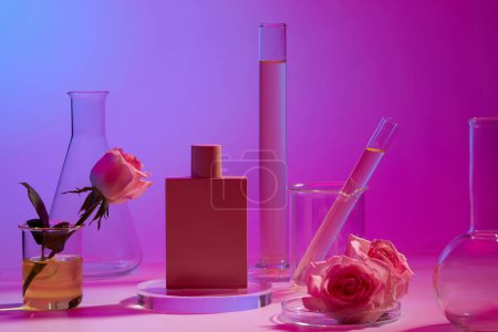 Photo for Pink perfume bottle standing on round transparent podium, displayed with laboratory glassware. Rose (Rosa) essential oil is very useful for perfume production - Royalty Free Image