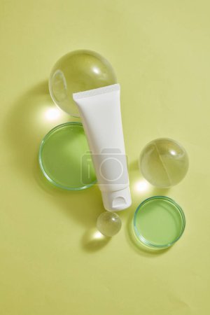 Photo for An empty label white tube decorated with glass transparent ball and petri dishes filled with green fluid. Cosmetic laboratory research and development - Royalty Free Image