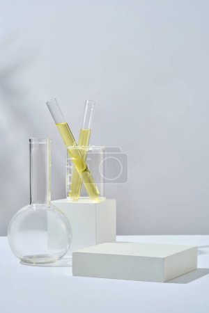 Reagenzglas mit gelber Flüssigkeit in einem Becher, der auf einem Würfelpodest steht. Leeres Rechteck-Podium für die Werbung für Schönheitsprodukte aus Limettenextrakt (Citrus aurantiifolia)