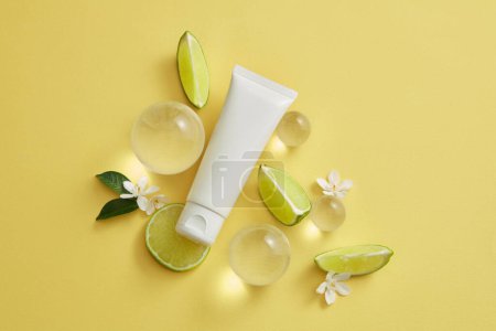 Photo for Several glass balls, small flowers and Lime slices arranged with an empty label tube. Lime (Citrus aurantiifolia) can be used to enhance skin condition - Royalty Free Image