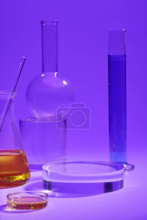 Measuring cylinder of blue fluid, conical flask and petri dish of orange fluid arranged with a round transparent podium. Laboratory concept