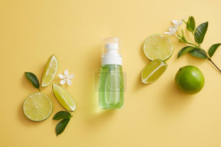 Photo for Green liquid is contained inside a pump bottle dispenser decorated with Lime slices and a flower branch. Empty label to promote beauty product extracted from Lime (Citrus aurantiifolia) - Royalty Free Image