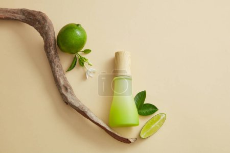 A blank label jar with wooden cap is decorated with Lime slice, tree branch, green leaves and white flower. Natural beauty product concept. Unbranded mockup of Lime (Citrus aurantiifolia) extract