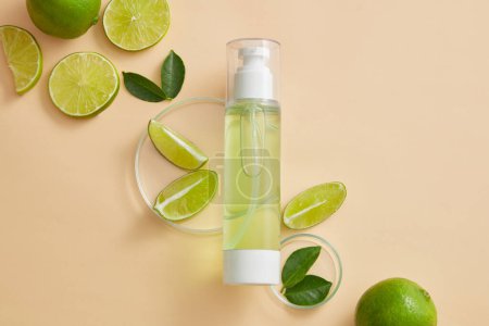 Photo for Empty label pump bottle dispenser displayed on beige background with petri dishes of Lime (Citrus aurantiifolia) slices and green leaves. Toner or serum cosmetic product promotion - Royalty Free Image