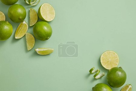 Against a pastel background, Lime slices and peels are arranged at the corners. Blank space to display beauty product extracted from Lime (Citrus aurantiifolia), copy space