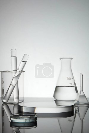 Photo for Test tubes, petri dish and erlenmeyer flask containing water, transparent podium in round shape with empty space for product presentation. Laboratory concept - Royalty Free Image