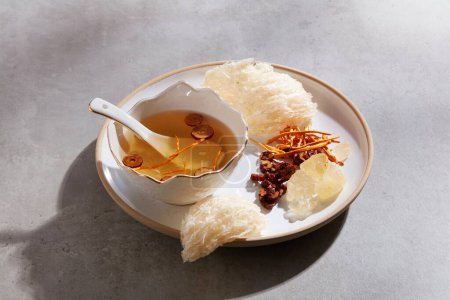 Edible bird nest displayed with a bowl of bird nest soup with jujube and cordyceps and rock sugar on a ceramic dish. A luxury combination for healthcare
