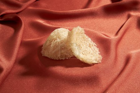 Some edible bird nest are arranged on top of a luxurious pink fabric background. Close-up view. Bird nest brings a lot of nutritional value for people