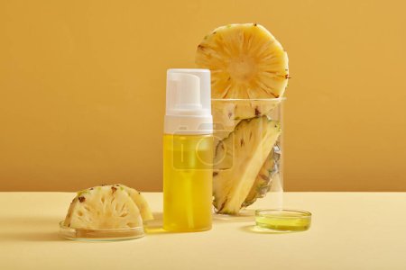 Photo for Pineapple slices is placed on petri dish and inside a glass beaker. An empty label bottle containing yellow liquid extracted from pineapple (Ananas comosus). Natural facial skincare - Royalty Free Image