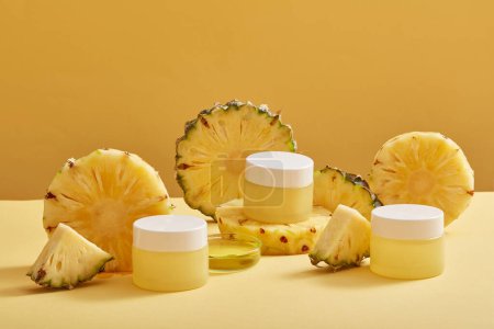 Three jars with empty label and a petri dish of pineapple essence displayed with pineapple slices. Pineapple (Ananas comosus) is rich in Vitamins C & E