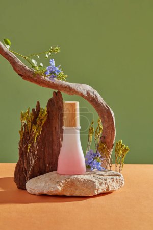 Foto de Una piedra con un frasco de etiqueta vacía en color rosa colocado, decorado con árboles y flores. Mugwort (Artemisia vulgaris) ayuda a eliminar la suciedad y la suciedad de la piel - Imagen libre de derechos