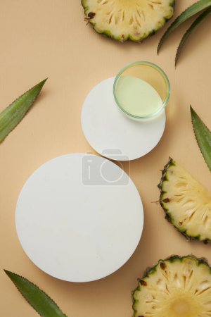 Zwei weiße runde Podeste mit einer gläsernen Petrischale aus flüssiger Essenz, die aus Ananas (Ananas comosus) gewonnen wird, dekoriert auf beigem Hintergrund. Natürliche Bio-Kosmetik-Konzept