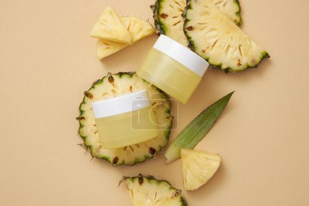 Photo for Two empty label jars arranged with pineapple slices on beige background with top view. Product mockup extracted from pineapple (Ananas comosus), ingredient in cosmetic production - Royalty Free Image