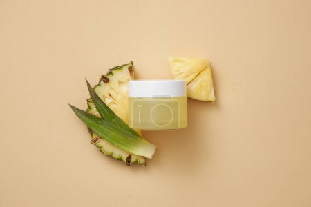 Over the pastel background, a jar without label is decorated with pineapple slices and leaves. Promoting cosmetic product extracted from pineapple (Ananas comosus)