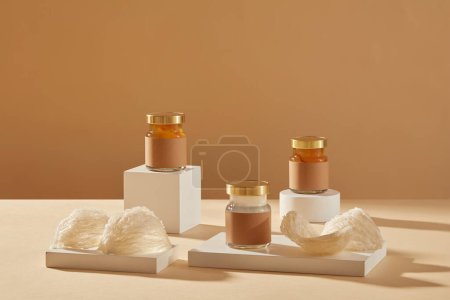 Photo for Some glass transparent jars and edible bird nests are arranged on white podiums or pedestals. Empty label for product mockup. bird nest is luxury dessert, very well-known in Korea and China - Royalty Free Image