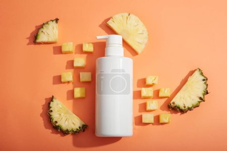 Photo for A white empty label pump bottle displayed with pineapple cubes and slices. Pineapple (Ananas comosus) is rich in Vitamins C & E. Product mockup - Royalty Free Image