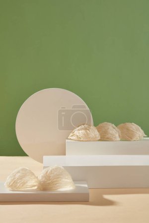 Edible bird nests placed on white podiums or pedestals decorated on pastel green background. Empty space for product presentation. Bird nest promotes healthy and glowing skin. Healthcare concept
