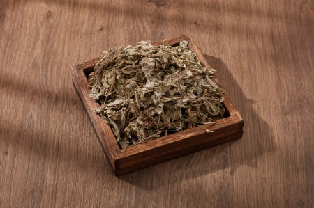 Un plato de madera con Mugwort se muestra en. La Mugwort (Artemisia vulgaris) se promueve por problemas digestivos, menstruación irregular y presión arterial alta.