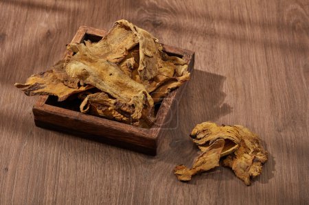 Foto de Raíz de ruibarbo y rizoma exhibidos en una bandeja de madera con fondo de madera. Raíz de ruibarbo y rizoma (Rhizoma Rhei) se utiliza principalmente para curar problemas digestivos - Imagen libre de derechos