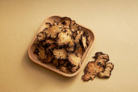 Téléchargez les photos : Un plat en bois de Szechuan Lovage Rhizome sur un fond clair. Szechuan Lovage Rhizome (Ligusticum striatum) a un goût épicé, arôme et chaleur, peut traiter les maladies - en image libre de droit