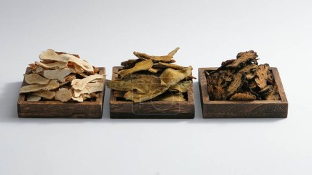 Téléchargez les photos : Trois plateaux en bois contenaient du Bai Zhu, de la racine de rhubarbe et du rhizome et du rhizome d'amour du Szechuan. Herbes pour améliorer la santé, très utiles en médecine traditionnelle - en image libre de droit