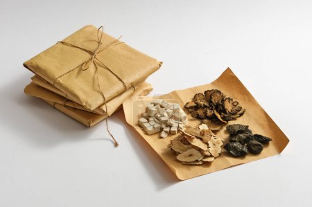 Foto de Poria cocos, Szechuan Lovage Rhizome, Bai Zhu y Dried aloe vera se colocan en un papel con algunos paquetes de medicamentos al lado. Medicina preciosa para la salud - Imagen libre de derechos