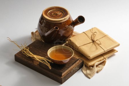 Photo for A wooden podium with a bowl of medicine and Dang Shen placed on, displayed with an earthen pot and some medicine packs. Chinese herbal therapy - Royalty Free Image