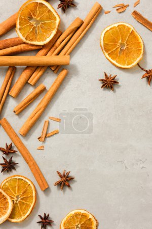 Photo for Dried orange slices, star anise and cinnamon sticks are decorated on minimalist background with blank space to promote cosmetic product extracted from these herbals. Benefiting health, skin and hair - Royalty Free Image