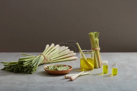 Photo for Bunches of lemongrass (Cymbopogon citratus) and some lemongrass placed on a wooden dish. Essential oil extracted from lemongrass contained in some glass transparent jars. Healthy concept - Royalty Free Image