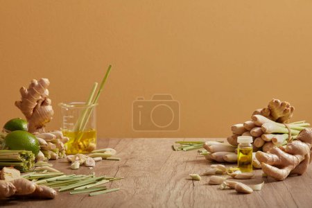 Téléchargez les photos : Le gingembre, la citronnelle et les citrons sont décorés sur une table en bois. pots en verre d'huile essentielle extraite de ces herbes, avantages pour la santé, la peau et les cheveux. Espace vide pour la présentation du produit - en image libre de droit