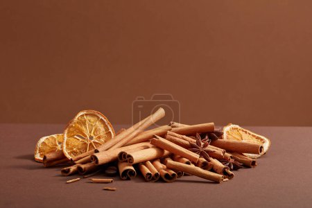Photo for Many cinnamon sticks, star anise and dried orange slices are decorated on a dark minimalist background. Healthy combination of herbals for health, skin and body - Royalty Free Image