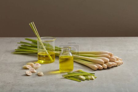 Photo for Two glass transparent jars containing essential oil extracted from lemongrass (Cymbopogon citratus) decorated with lemongrass on minimalist background. Healthier skin and hair - Royalty Free Image