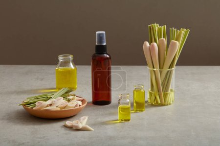 Photo for An empty label bottle displayed with some jar of essential oil extract from lemongrass (Cymbopogon citratus) and a wooden dish with lemongrass placed on. Use as drinking to get rid of coughs - Royalty Free Image