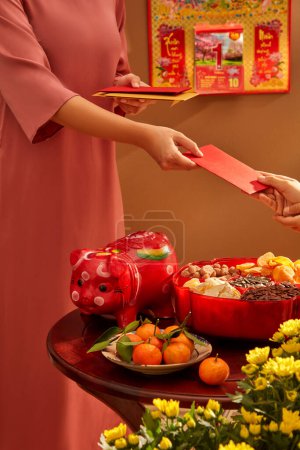 Téléchargez les photos : On se donne des enveloppes rouges porte-bonheur. Les vacances habituelles en Asie. Vue de face - en image libre de droit