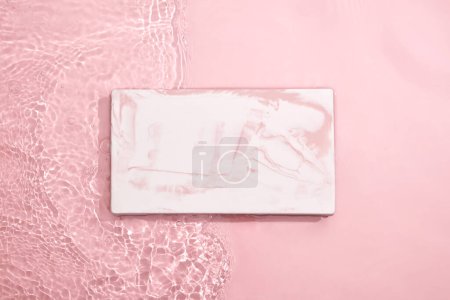 Téléchargez les photos : La conception de la marque de produits cosmétiques et de beauté peut être affichée sur une plate-forme rectangulaire en marbre. Fond rose clair avec de l'eau - en image libre de droit