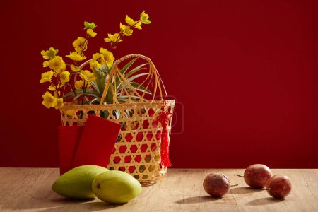 Foto de Algunos mangos y maracuyá colocados en la mesa. Una cesta con flores de albaricoque para el concepto de vacaciones de año nuevo chino. Vista frontal - Imagen libre de derechos