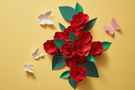 Téléchargez les photos : Un tas de fleurs de papier rouge avec peu de papillons dans beaucoup de couleurs. Fleurs en papier 3d isolées sur fond jaune, éléments décoratifs. Couché plat, vue du dessus - en image libre de droit
