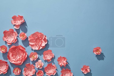 Téléchargez les photos : Beaucoup de fleurs roses décorées sur fond bleu minimaliste pour les concepts de printemps. papier découpé et style artisanal. Pose plate, frais généraux - en image libre de droit
