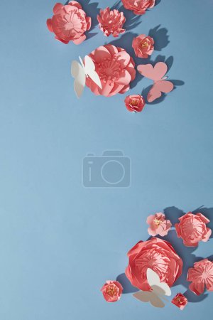 Téléchargez les photos : Fleurs en papier rose avec différentes tailles disposées dans le coin décoré sur fond bleu. Espace vide pour ajouter du texte ou un produit pertinent pour les fleurs. - en image libre de droit