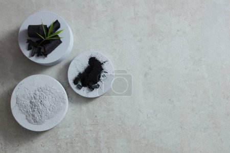 Photo for Flat lay of broken black activated charcoal and powder placed on podiums - Royalty Free Image