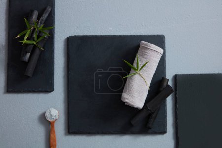 Foto de Una toalla y bambú negro colocados sobre piedras negras con forma rectangular y cuadrada - Imagen libre de derechos