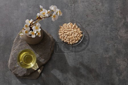 Photo for A bird's-eye view of flower pot, a glass of tea and nuts placed on a big stone. Cement background - Royalty Free Image