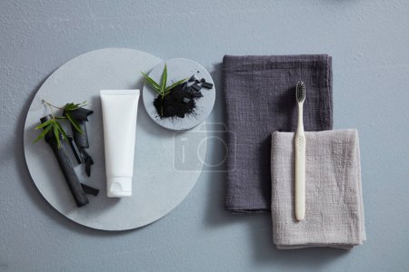 Téléchargez les photos : Pose plate de tube cosmétique avec charbon activé en bambou. Concept de soins dentaires. Vue de dessus, vue aérienne - en image libre de droit