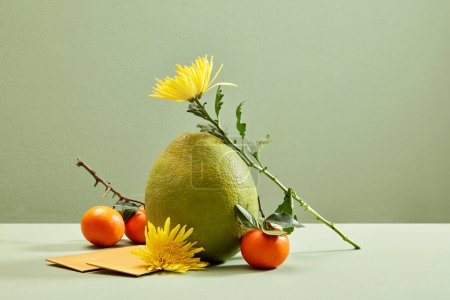 Foto de Pomelo, naranjas mandarinas, sobres amarillos y flores amarillas exhibidas sobre fondo pastel. Concepto de celebración Tet - Imagen libre de derechos