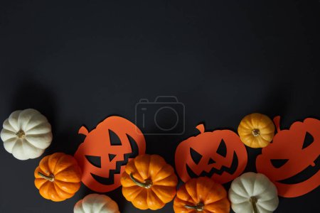 Halloween-Konzept mit vielen Kürbissen und Papierkürbissen auf schwarzem Hintergrund. Leere Räume