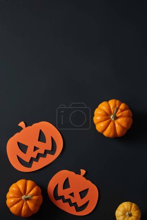 Einige Kürbisse und Papierkürbisse. Halloween-Dekorationen auf schwarzem Hintergrund. Leerraum für Produktwerbung